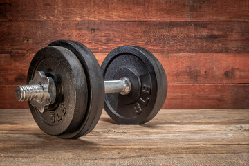 cast iron dumbbell on a grunge wooden deck - fitness concept