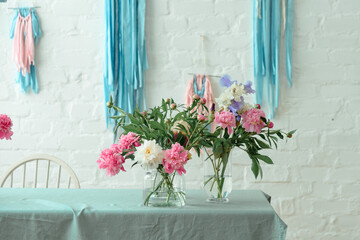 Pink peonies in glass vase. Flowers on white table near the window. Morning light in the room. Beautiful peony flower for catalog or online store. Floral shop and delivery concept. Banner. Copy space