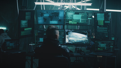 A male hacker in a casual jacket on a chair, hacking a nuclear weapon launch on a computer with a...