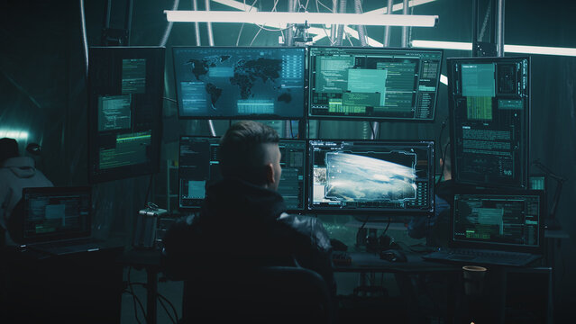 A male hacker in a casual jacket on a chair, hacking a nuclear weapon launch on a computer with a countdown in a dark cybercriminal hideout - Powered by Adobe