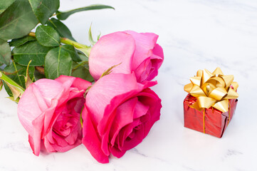 Fototapeta premium A simple arrangement with a flower and a heart shape decoration. Rose and gift box on marble background.