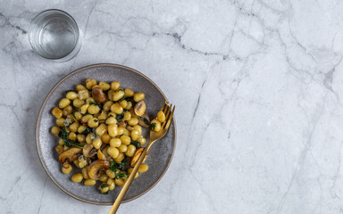 Plate with cooked potato gnocchi with butter sauce, mushrooms, spinach and cheese. Top view with copy space.