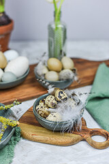 Dekoration Ostern mit Eiern, Federn und Frühlingsblumen auf einem Tisch mit Teller, Schale, Blumenvase und Holzbrett, Frühling dekorieren, Tulpe, Hyazinthe
