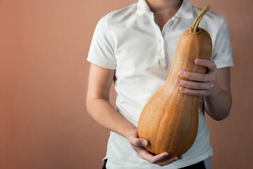 Young man holding a Halloween pumpkin on a pink background.
Autumn fall concept.
Pumpkin in male hands.