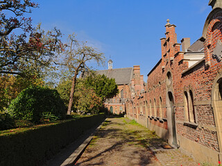 Cobble street along a park with medieval brick houses and church in Antwerp beguingte