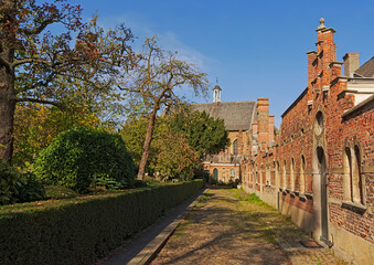Cobble street along a park with medieval brick houses and church in Antwerp beguingte