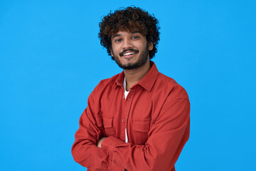 Smiling young curly indian cool guy standing isolated on blue background. Happy ethnic stylish...