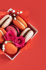 Tasty french macarons in a box on a red background. Concept for Valentine's day.
