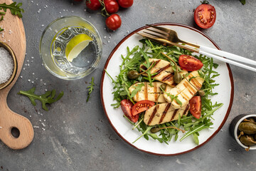 Fresh salad with grilled halloumi cheese, tomatoes, capers, lettuce and arugula. ketogenic paleo diet. Delicious breakfast or snack, Clean eating, dieting, vegan food concept. top view