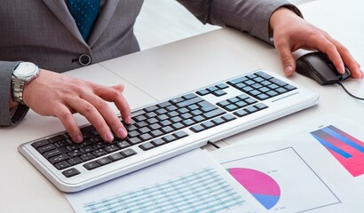 Finance professional working on keyboard with reports