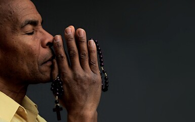 man praying to god with hands together Caribbean man praying with grey background stock photo