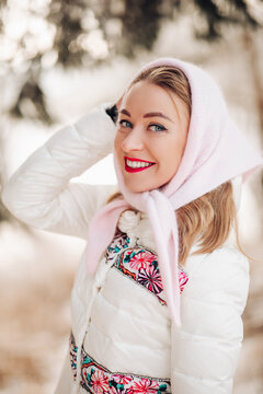 Beautiful Russian woman in a headscarf, portrait. A lovely woman smiles and looks at the camera in winter.