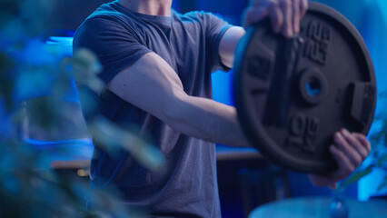 Headless male person spinning heavy plate burning shoulders exercise at home