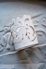 white clay openwork vase for dried flowers on the sand