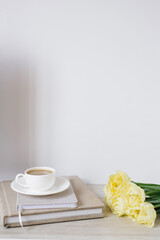 Creative composition of beautiful delicate yellow tulips, notebooks and a cup of coffee on the desktop of a freelancer or blogger
