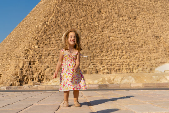 Cute little girl dancing in front of the Cheops pyramid on the Giza plateau.