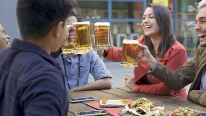 Multiracial young people having fun cheering with beer at brewery bar restaurant outdoor