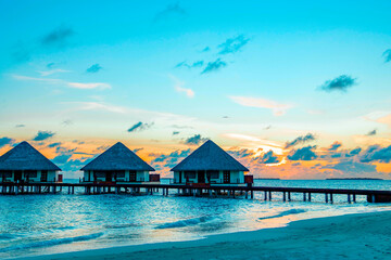 view of the water villas at sunrise in the Maldives, the concept of luxury travel