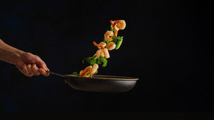 Sea food. A professional chef prepares seafood with vegetables and herbs in a frying pan. Levitation. Black background. Healthy vegetarian, diet food. Restaurant, hotel, banner.
