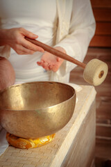 A woman performs Tibetan singing bowl therapy with a man lying under a white sheet. Relaxing meditation.
