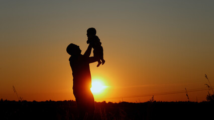  Happy father throws up his baby, Unrecognizable silhouette at sunset