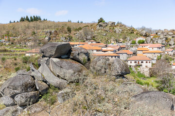 a view of Castelo village (Tel&otilde;es) with big boulders in the foreground, Vila Pouca De Aguiar, district of Vila Real, Portugal - April 2019