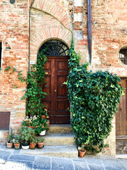 Obraz na płótnie Canvas Via del Poggiolo street view in Montepulciano, Toscana, Italy. Old Italian brick house with arched door and wall covered ivy. Tuscany