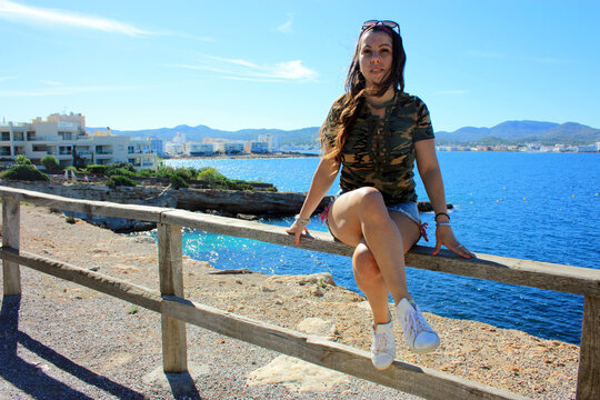 girl on fence posing on vacation enjoying the blue color of summer in ibiza