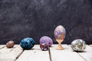 Original painted Easter eggs on a dark background. iolet, blue, gray Easter eggs with marbled transitions, painted with natural dyes. Space ornaments on food