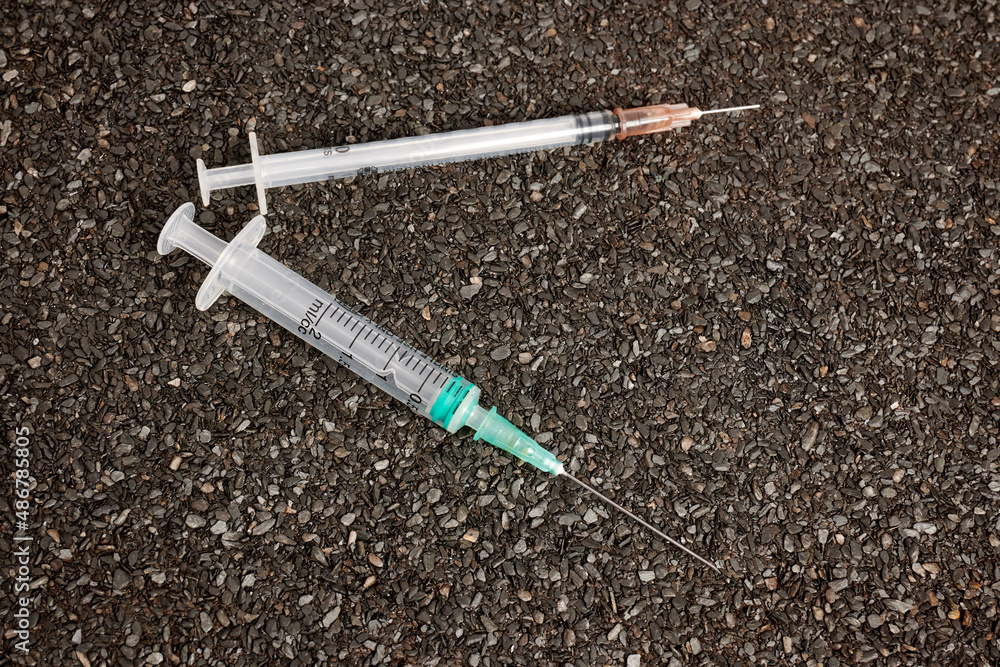 Poster syringes on ruberoid textured surface. injection syringes on the ground. needles with narcotics. use