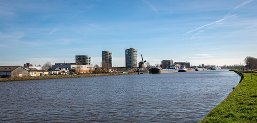 Panoramic view of modern apartments and old windmill along channel 