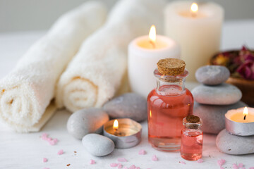 Fototapeta na wymiar Concept of spa treatment in salon. Natural organic oil, towel, candles as decor. Atmosphere of relax, serenity and pleasure. Anti-stress and detox procedure. Luxury lifestyle. White wooden background