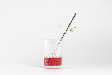 a skeleton dances a striptease on a metal straw in a glass of juice