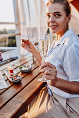 Woman eating fresh oysters and drinking chilled prosecco wine on the summer sunset. Seafood delicacies
