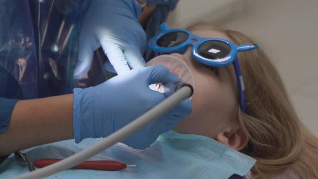 little girl with oral dilator at dentist's appointment. polishing of teeth