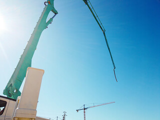 Jib of concrete pump truck ready for concrete conveying at construction site. Arm of concrete pump against sky at background. Truck mounted concrete pump ready for cement casting © Philipp Berezhnoy