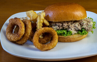 tuna sandwich  with a side of fries and onion rings