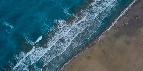 Top down aerial view of waves on the beach. Sea waves and sandy beach. Evening surf