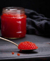 fresh grainy red caviar in a glass jar on a wooden table
