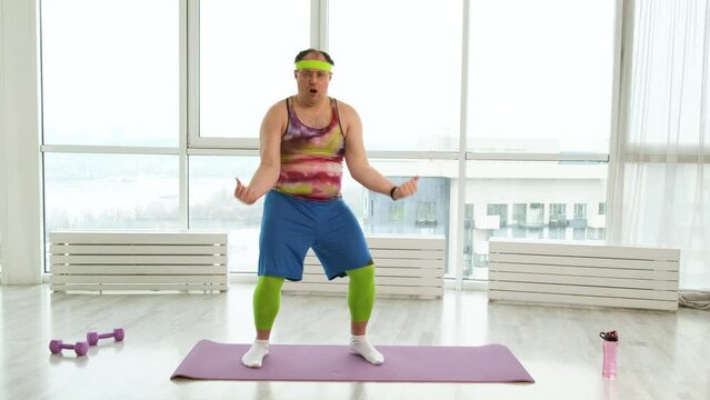 Expressive overweight man in 90s style clothes dancing in white studio. Happy cheerful fat young man dancing and having fun