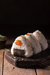 Japanese traditional snack rice balls triangle onigiri with raw salmon and red caviar on a dark...