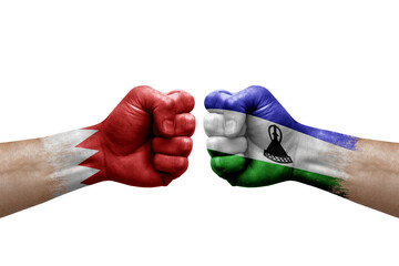 Two hands punch to each others on white background. Country flags painted fists, conflict crisis concept between bahrain and lesotho