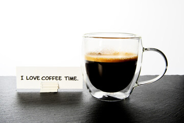 Coffee in a transparent cup on the table. Caption: I love coffee time. White background. Copy space.