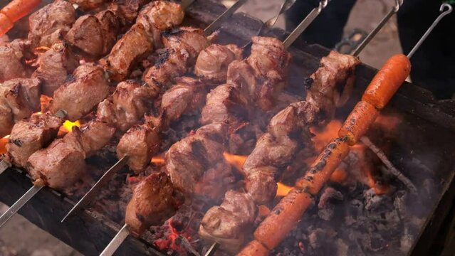 a man roasts meat on a fire. Close-up of hands and shish kebab. Cooking pork neck on the grill. Roasted carrots. Fatty food, festive food of the CIS countries. May 1, labor day. Not vegan food.
