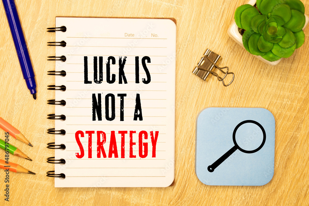 Poster luck is not a strategy text on a notebook on office desk.