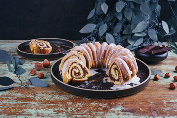 Traditional Polish babka bundt cake with hazelnuts, chocolate and icing sugar glaze served as close-up on a Nordic design plate