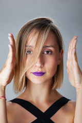 Beautiful blond girl with purple lipstick studio portrait. Hand gestures