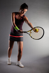 Professional female tennis player. Girl swinging racket preparing to serve.