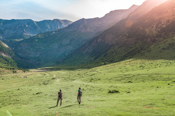 Fototapeta na wymiar Young Couple hiking in a beautiful valley between mountains during the sunset. Discovery Travel Destination Concept.