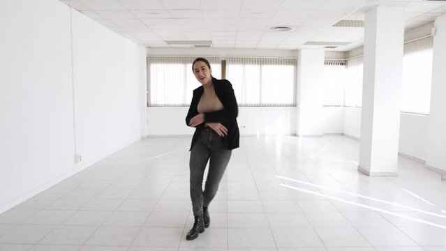 Cheerful young rental estate woman agent dancing in a new empty office after closing a purchase or rental agreement. High quality 4k footage